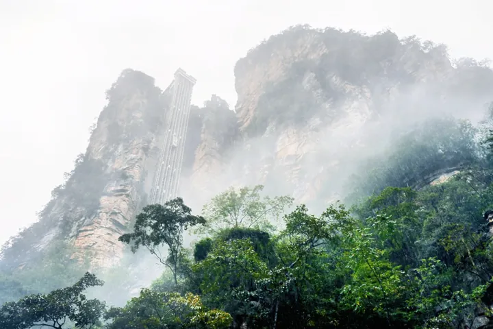 Elevator structure visible against misty cliffs and forest in Zhangjiajie